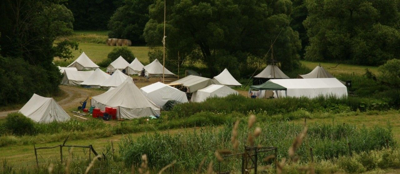 Zeltplatz mit aufgebauten weißen Zelten von einer Anhöhe fotografiert
